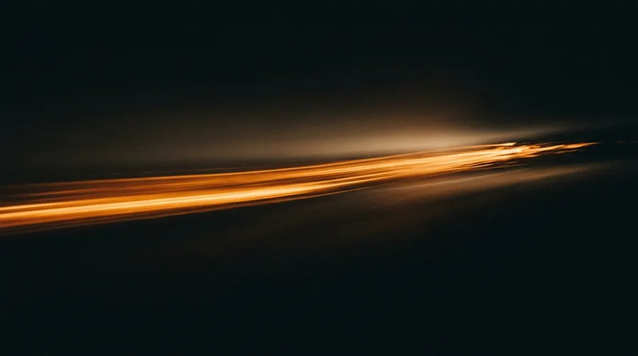 A streak of orange light moving fast across a dark frame